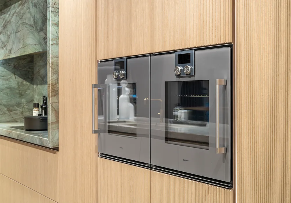 Cuisine design i-luminate avec appareils Gaggenau, façades en chêne clair et élégant quartzite.