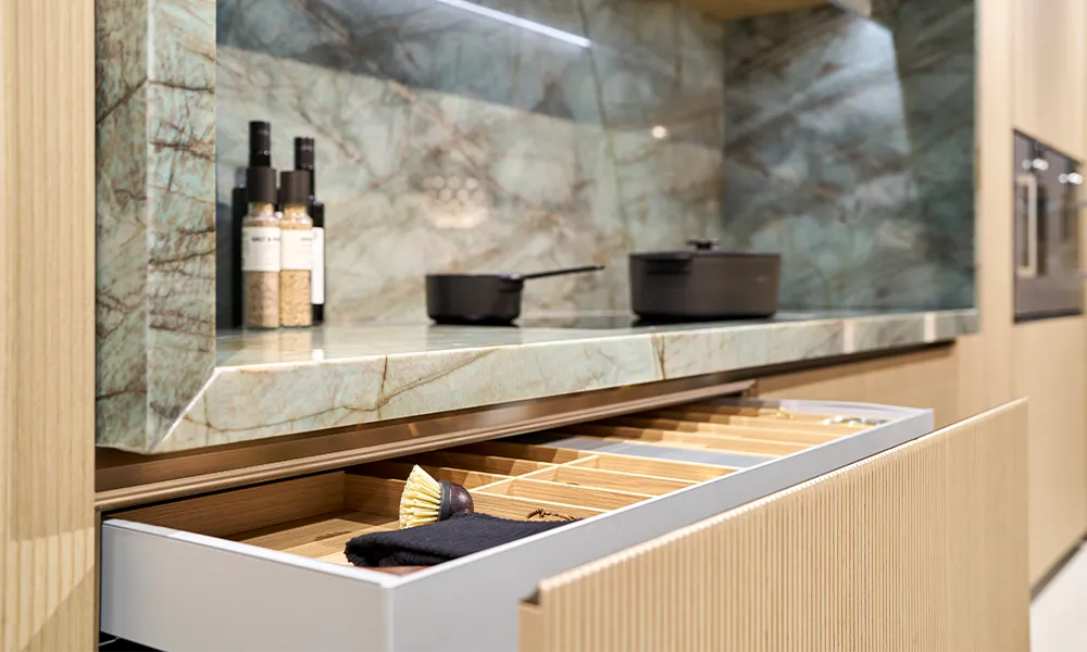 i-luminate Premiumküche mit Auszügen und individueller Innenausstattung und hellen Besteckeinsätzen aus Holz.